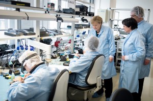 Guido Bergmann, Bundeskanzlerin Angela Merkel im Gespräch mit Mitarbeitern im Reinraum bei einem Rundgang beim Raumfahrttechnik hersteller Jena-Optronik, Mai 2013, Bundesbildstelle (www.bundesbildstelle.de/ collections/9365065/ _1365752805