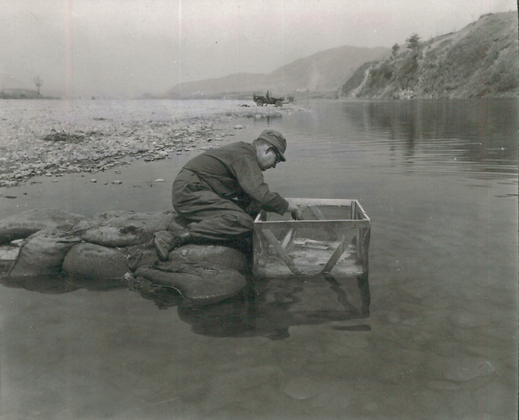 Abb. 3: A laboratory technician of the 4th Sig Bn Corps 8th Bat washes prints in the Hongomon-Gang river in Korea using a fine weave screen basket. The sandbag pier was constructed in order to reach water of sufficient depth and rate of flow to wash prints properly. No other means of washing prints properly. US Army photograph by CPL C.E. Abrahamson, 18 April 1951, National Archives Washington, 111-SC-364984