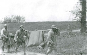 Drei Soldaten transportieren einen weiteren Soldaten auf einer Behelfstrage. Aus dem Buch von Ulrich Hägele: Walter Kleinfeldt: Fotos von der Front 1915-1918, S. 172 © Waxmann Verlag