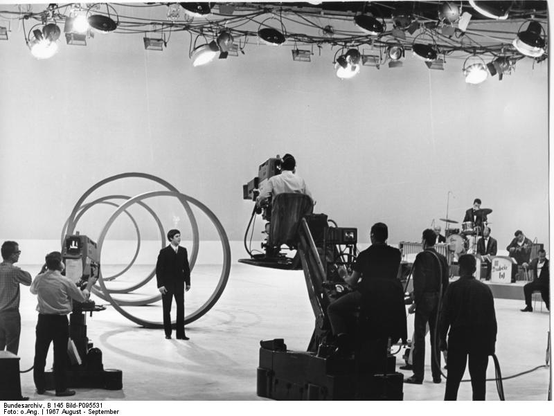 Berlin-West: 25. Große Deutsche Funkaustellung 1967 in Berlin: Proben zur Farbfernsehveranstaltung. „Show ist Show“ aus der Deutschlandhalle, Berlin 1967, Fotograf unbekannt, Presse- und Informationsamt der Bundesregierung - Bildbestand (B 145 Bild), Quelle: Wikimedia Commons / Bundesarchiv, B 145 Bild-P095531. Lizenz: CC-BY-SA 3.0 https://commons.wikimedia.org/wiki/File:Bundesarchiv_B_145_Bild-P095531,_Berlin,_Funkausstellung,_Proben_f%C3%BCr_Fernsehshow.jpg https://creativecommons.org/licenses/by-sa/3.0/de/deed.en